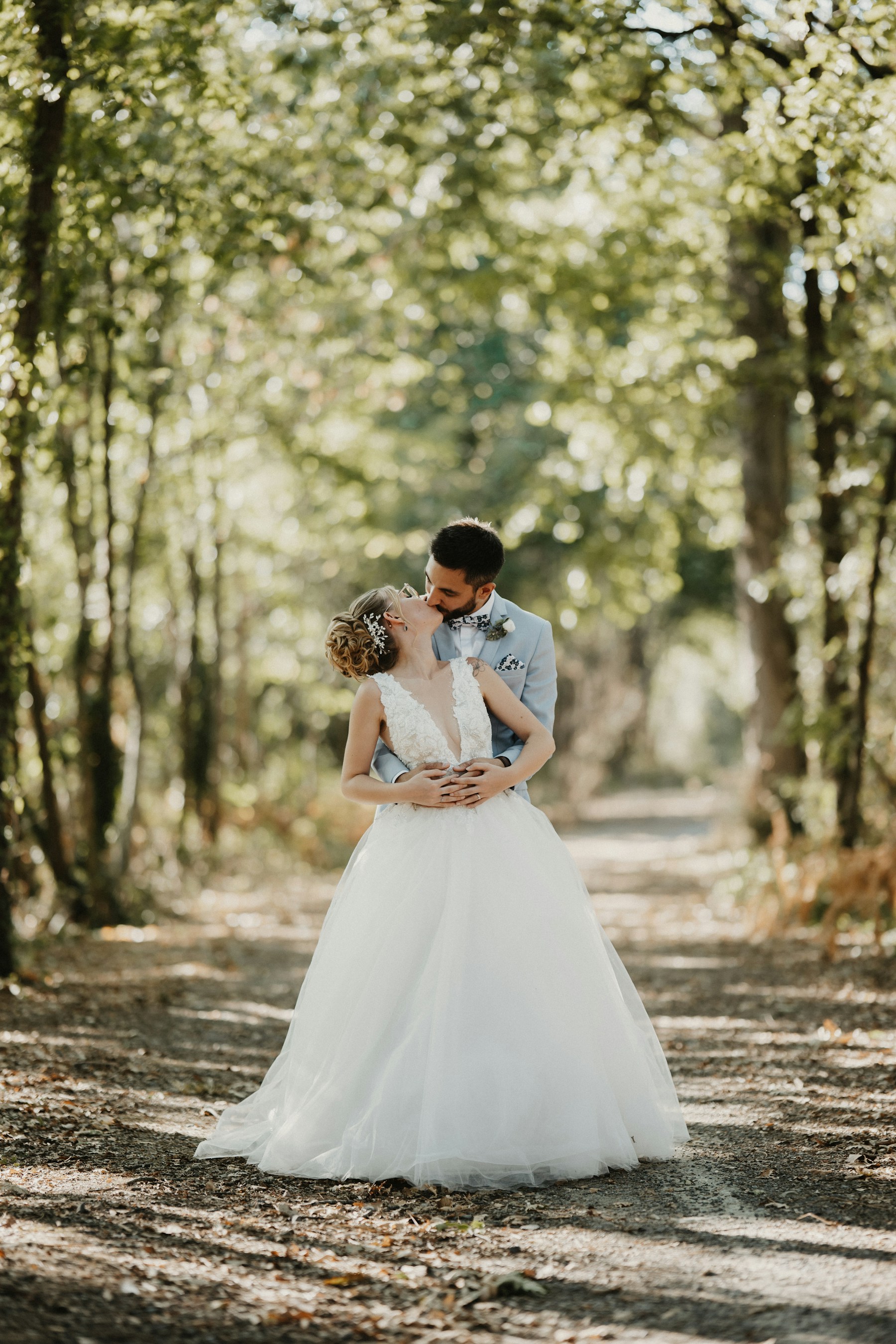 A wedding couple standing together on a sunlit forest path